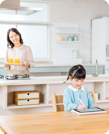 キッチンで見守る保護者と、タブレットで学ぶお子さま